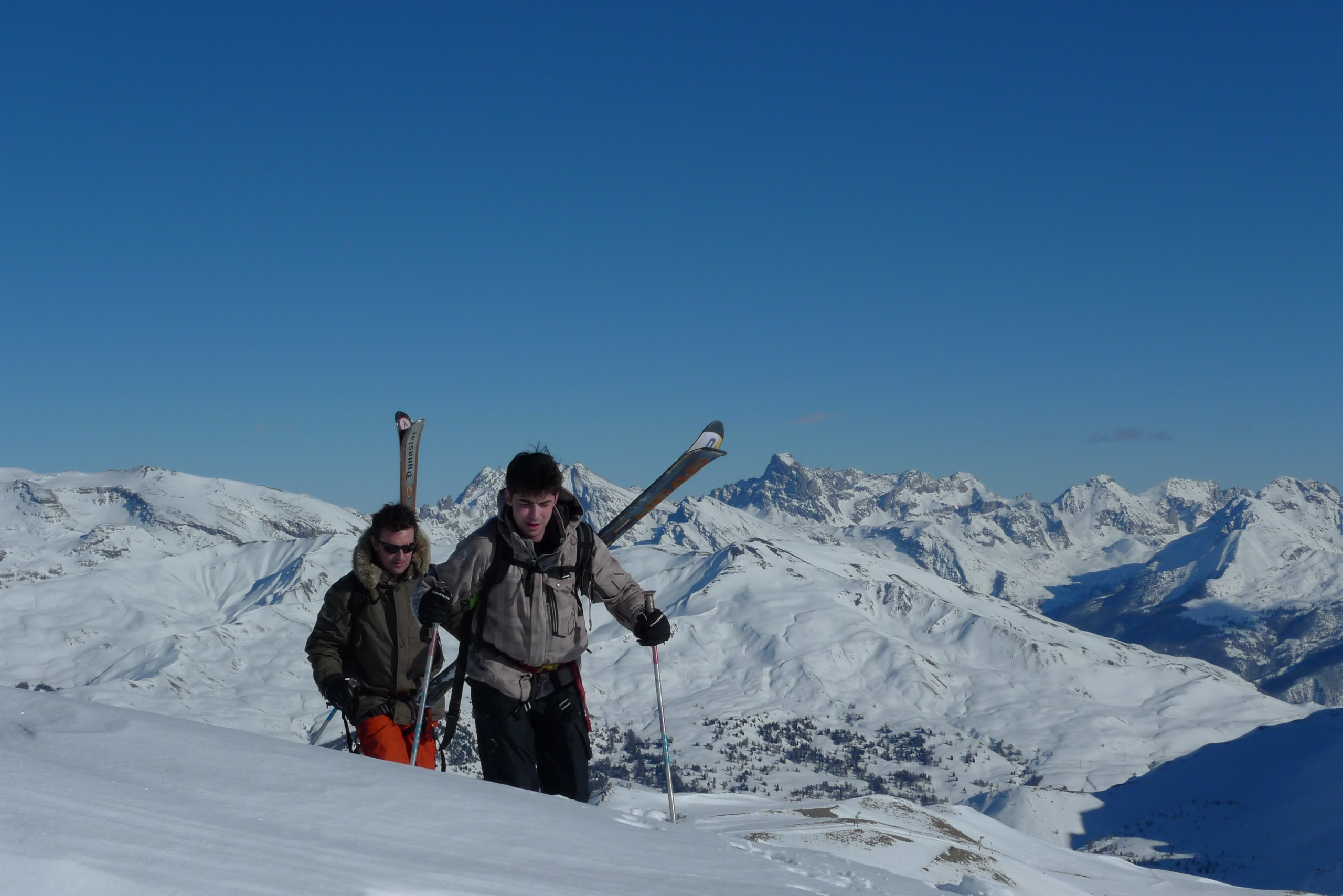 Deux skieurs monte ski sur le dos, avant une descente hors piste sur Vars et Risoul en compagnie de leur guide de montagne.